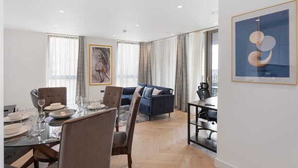 Un salon moderne comprenant un coin repas, un canapé bleu et une grande fenêtre avec des rideaux.
