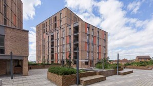 Un bâtiment moderne avec une façade en briques, de nombreux balcons et une cour intérieure agrémentée de jardinières.
