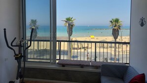 Een balkon met uitzicht op het strand, fitnessapparatuur en een bank.