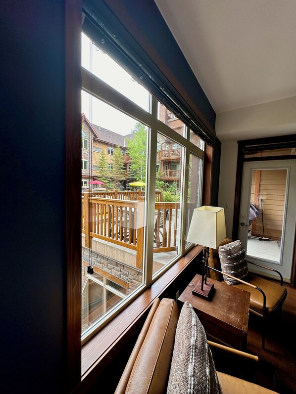 Una habitación con un ventanal grande, muebles de madera y vistas a un balcón con mobiliario exterior.