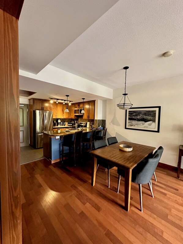 A modern kitchen with wooden cabinets, stainless steel appliances, and pendant lighting.
