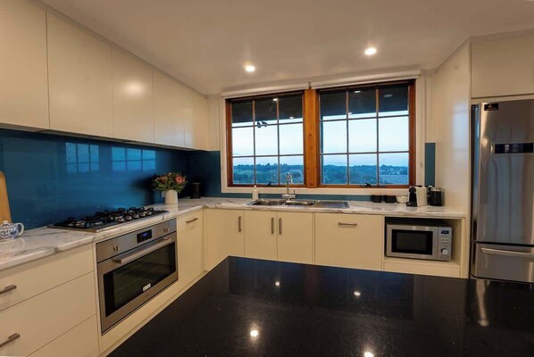 A modern kitchen with a large window, stainless steel appliances, and a black countertop. - Farm Stay, Picturesque views (Balhannah)