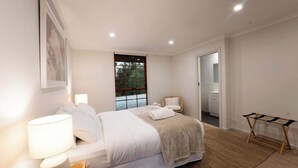 Een slaapkamer met een bed, bedlampen, een raam, een stoel en een klein tafeltje.