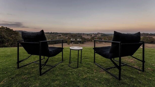 Twee zwarte stoelen met kussens, een klein rond tafeltje en uitzicht op het landschap.