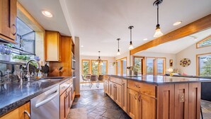 A modern kitchen with wooden cabinets, a large island, and pendant lighting.
