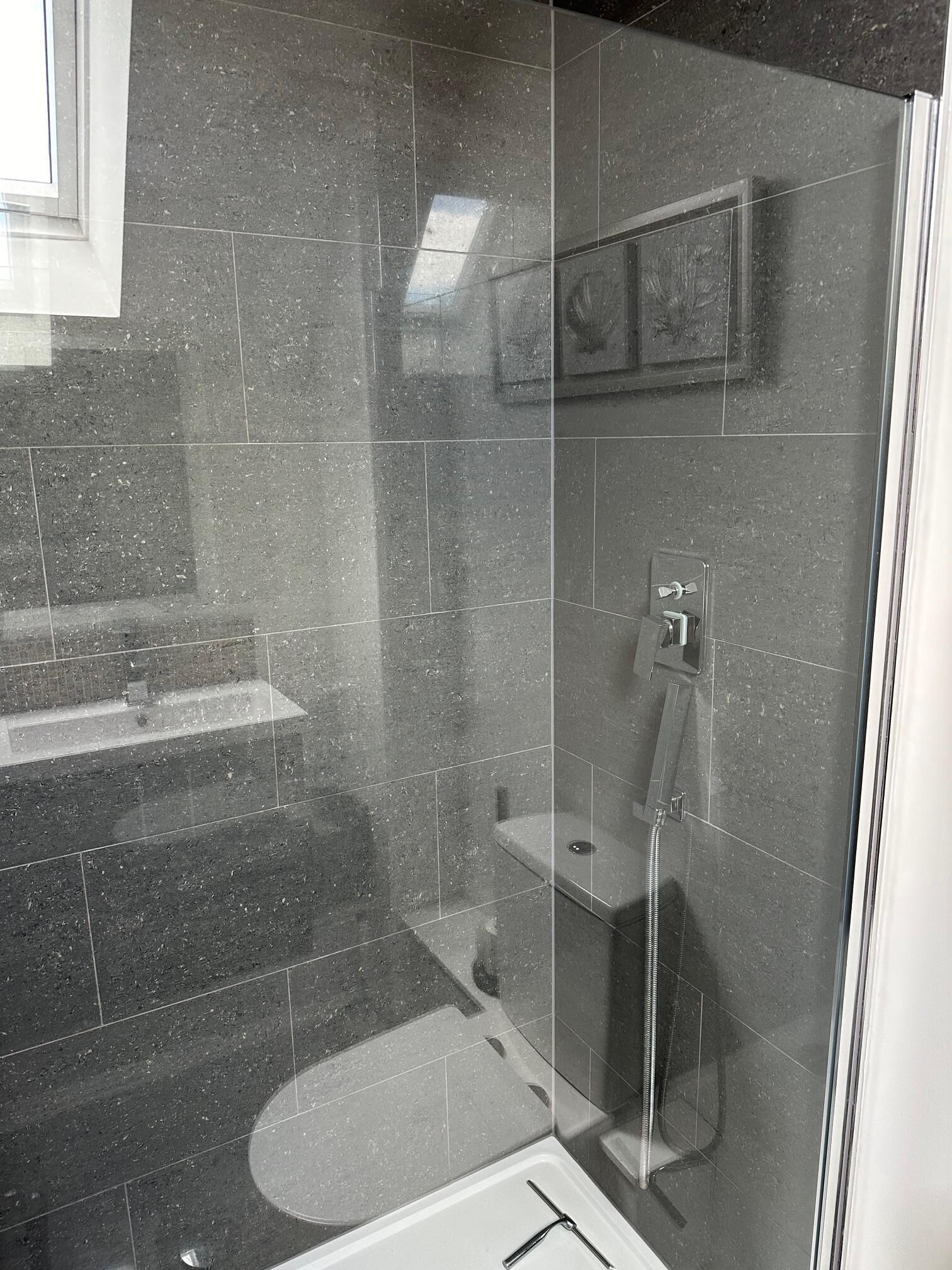 Un baño moderno con ducha envuelta en vidrio, lavamanos integrado y un inodoro.