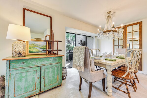 A dining area with a wooden table, chairs, a chandelier, and a green painted cabinet.