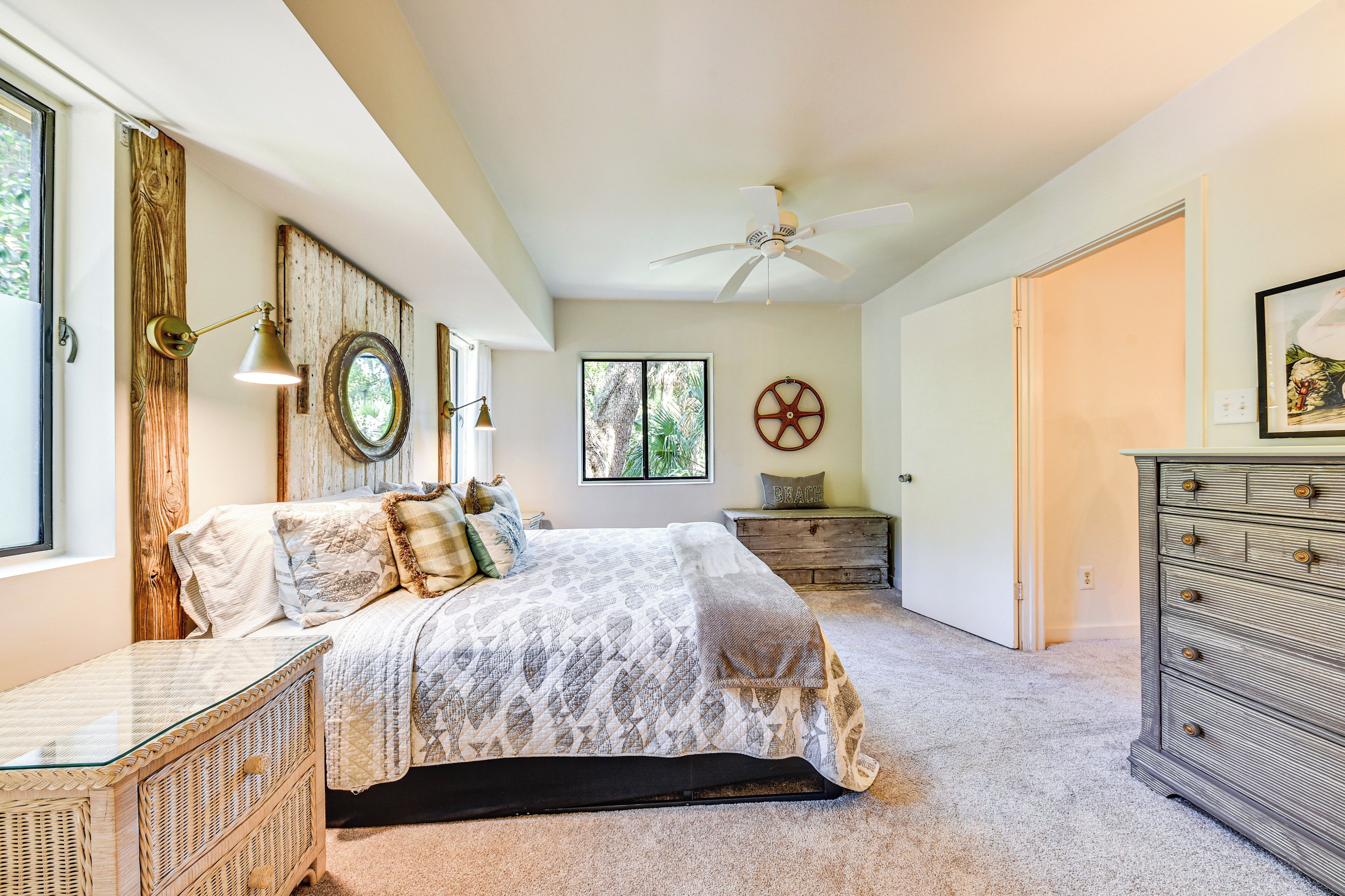 A bedroom with a bed, a dresser, a nightstand, a wall clock, and a ceiling fan.
