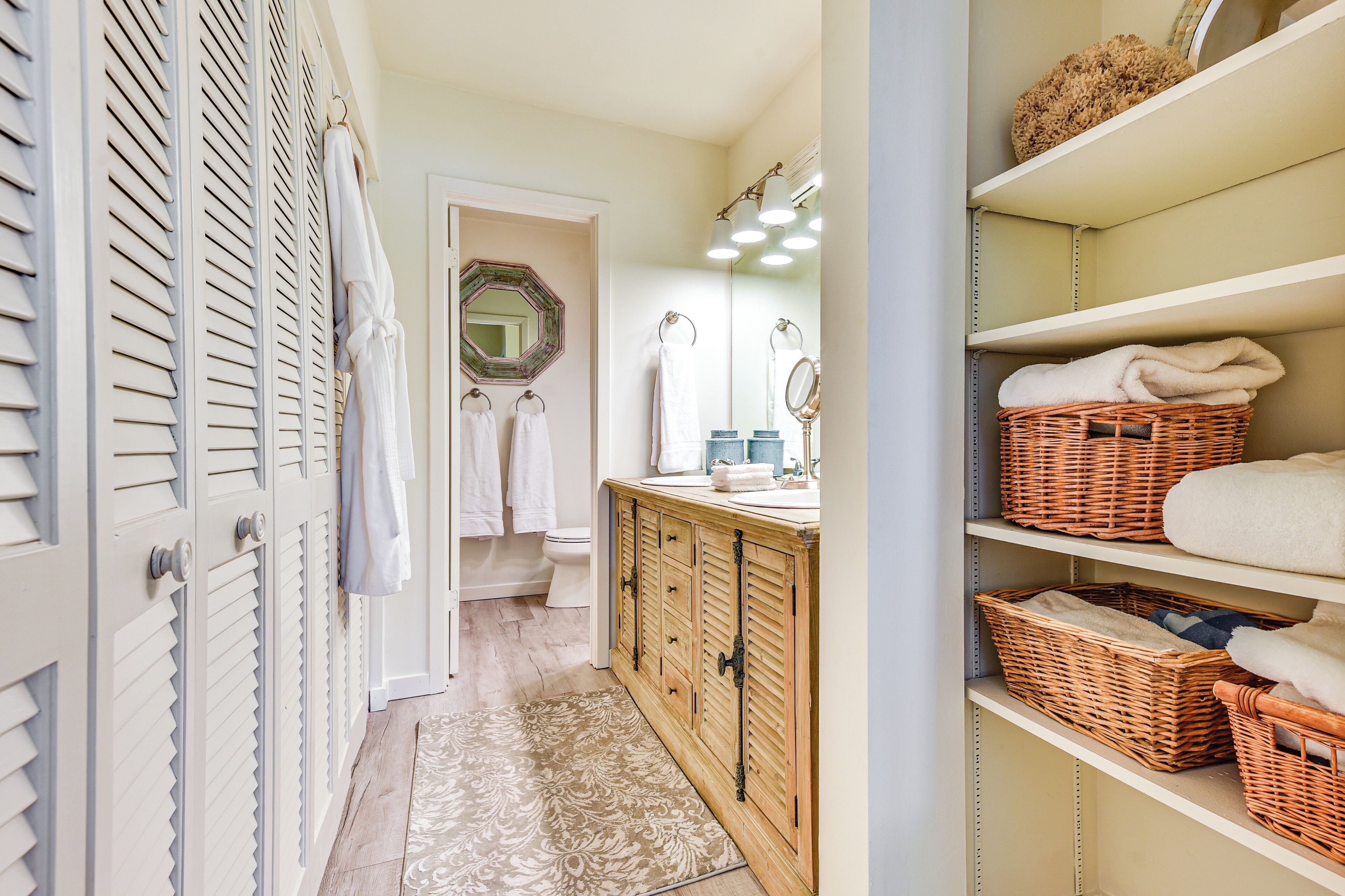 A well-organized bathroom with a wooden vanity, shelves with baskets, and a mirror.