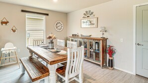 A dining area with a wooden table, white chairs, a high chair, and a cabinet with glass doors. - 10 Mi to Dtwn: Spacious San Antonio Home! (San Antonio)