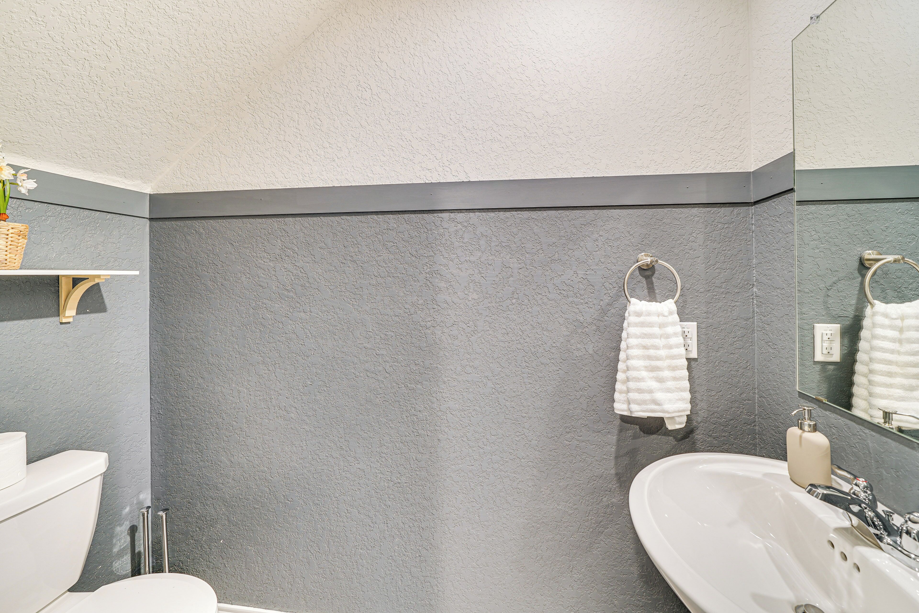 A bathroom with a white sink, a mirror, and a towel rack.
