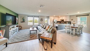 A spacious living room with a large sofa, a coffee table, and a TV. There is a kitchen in the background with a dining area. - 10 Mi to Dtwn: Spacious San Antonio Home! (San Antonio)