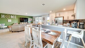 A modern kitchen with white cabinets, a central island, and a dining area with white chairs. - 10 Mi to Dtwn: Spacious San Antonio Home! (San Antonio)