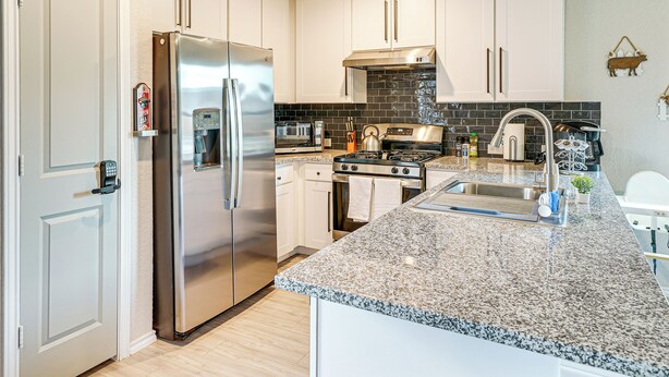 A modern kitchen with stainless steel appliances, white cabinets, a granite countertop, and a black backsplash. - 10 Mi to Dtwn: Spacious San Antonio Home! (San Antonio)