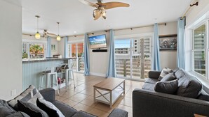 A spacious living area with a sofa, a coffee table, and a TV mounted on the wall. - Gulf View 23 (Gulf Shores)