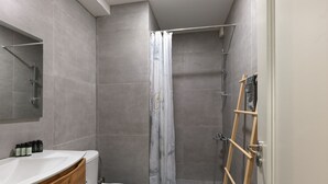 A modern bathroom with a toilet, sink, and shower. - Modern Living in Kolonaki (Athens)