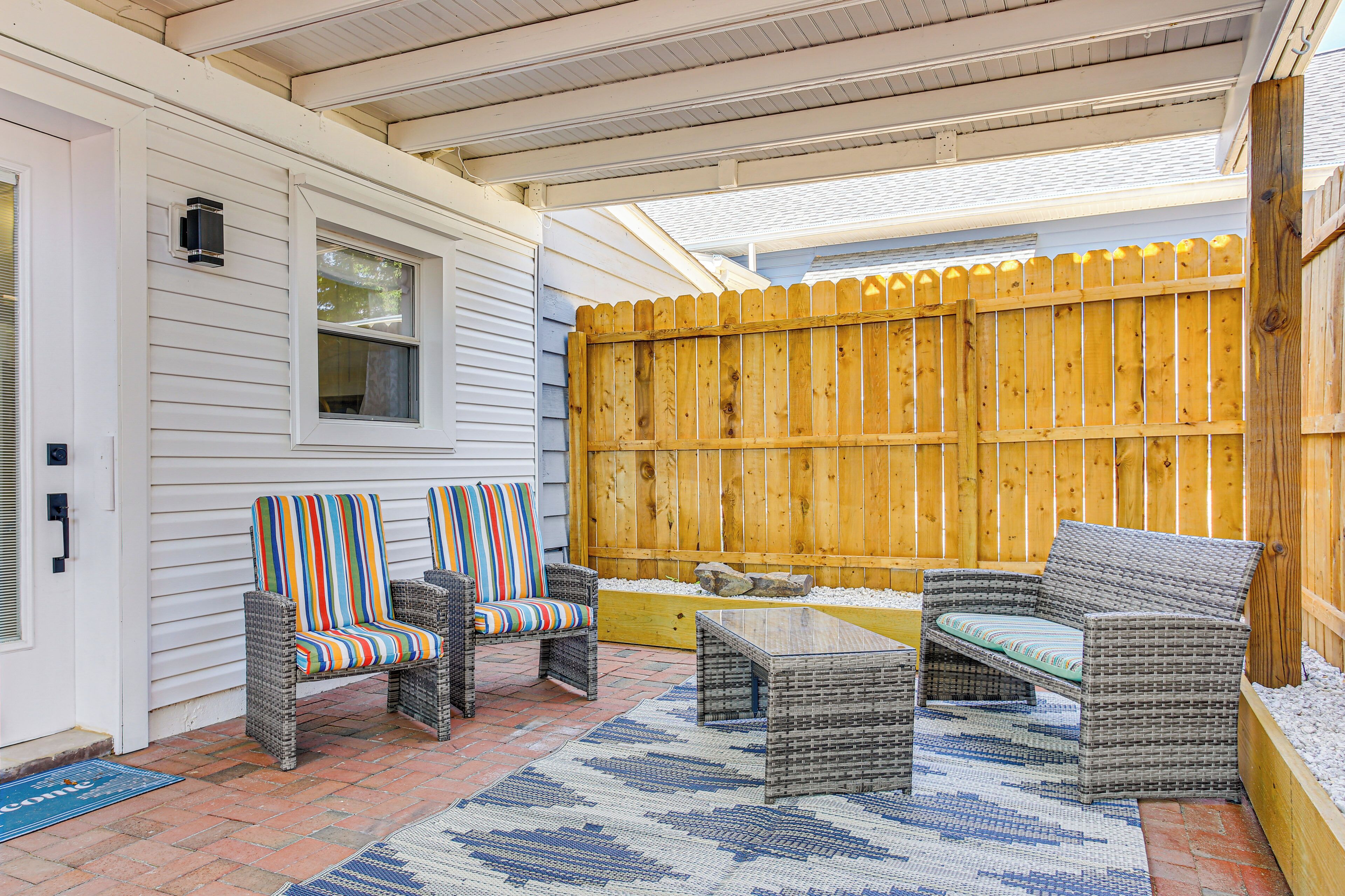 A covered patio with wicker furniture, a wooden fence, and a window.