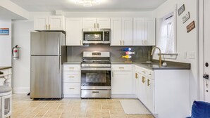 A modern kitchen with white cabinets, stainless steel appliances, and a tiled floor.