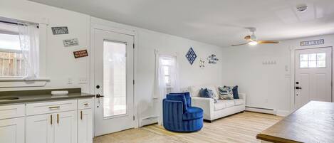 A spacious kitchen with white cabinets, a blue chair, and a dining table.