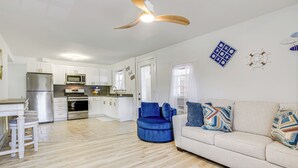 A modern kitchen with white cabinets, stainless steel appliances, and a ceiling fan.
