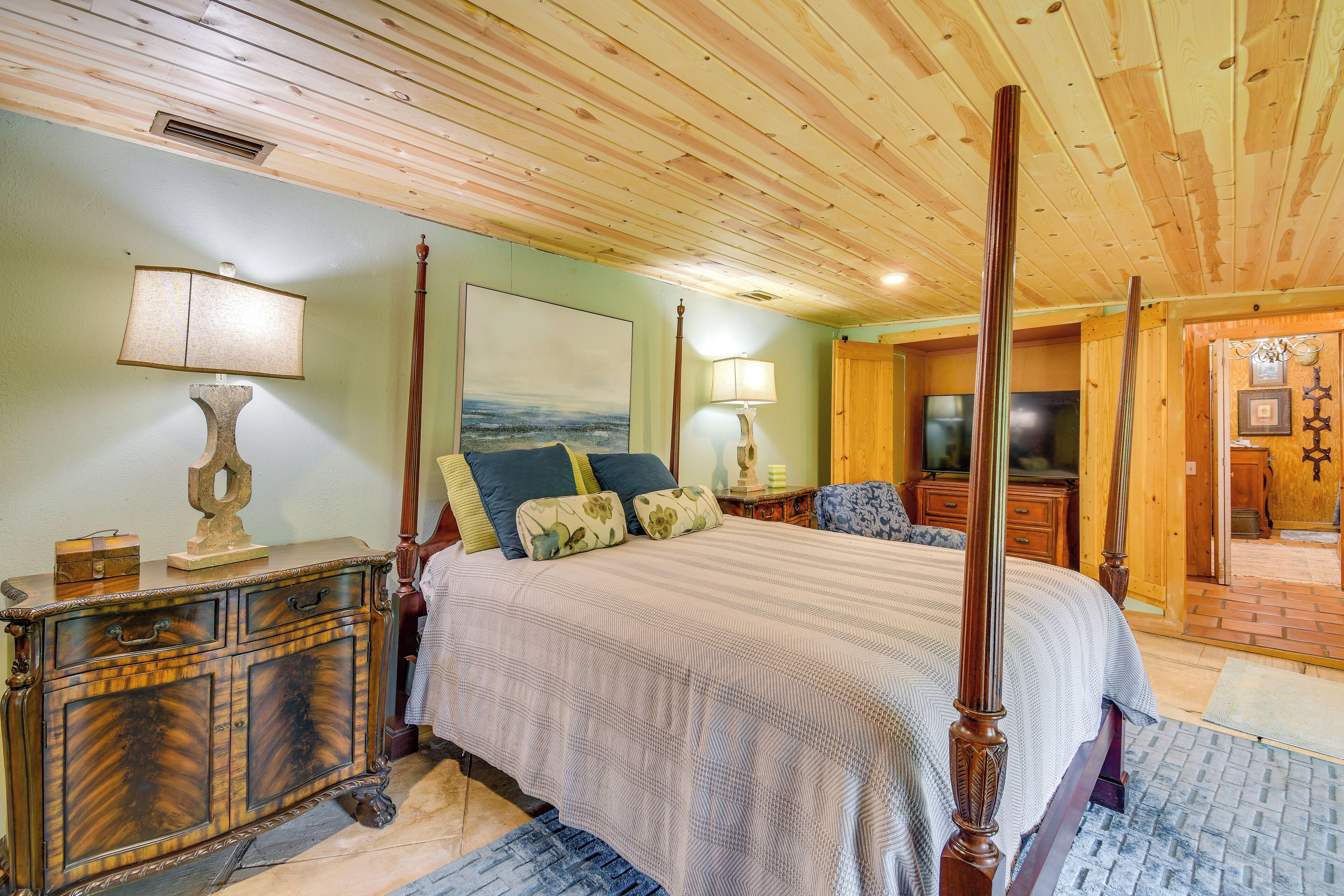 A spacious bedroom with a large bed, wooden headboard, and a classic dresser.