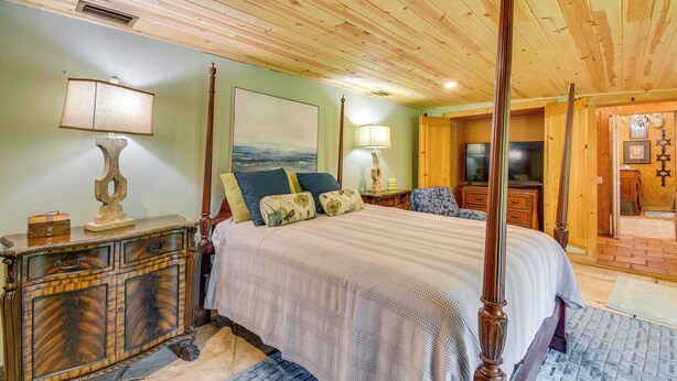 Un dormitorio amplio con una cama grande, cabecera de madera y una cómoda clásica.