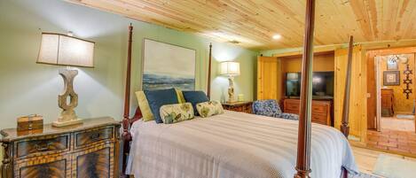 A spacious bedroom with a large bed, wooden headboard, and a classic dresser.