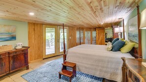 Un dormitorio amplio con una cama grande, techo de madera y vistas a un patio exterior por una puerta de vidrio.