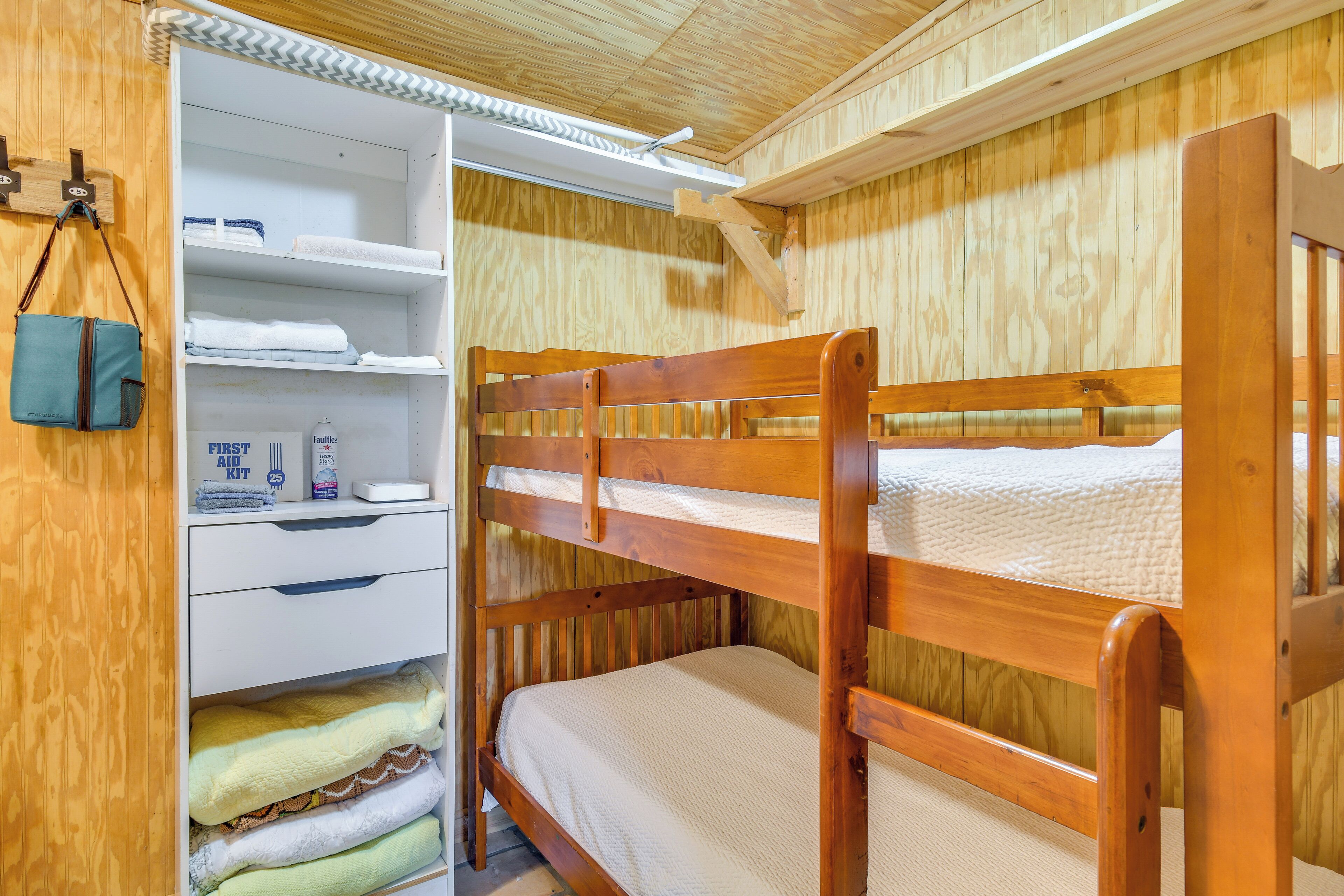 A bunk bed with a wooden headboard and a white storage unit with shelves.