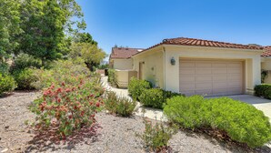 A residential house with a tiled roof, a garage, and a landscaped garden with various shrubs and a tree. - Escondido Townhome w/ Gas Grill + Golf Acess! (Escondido)