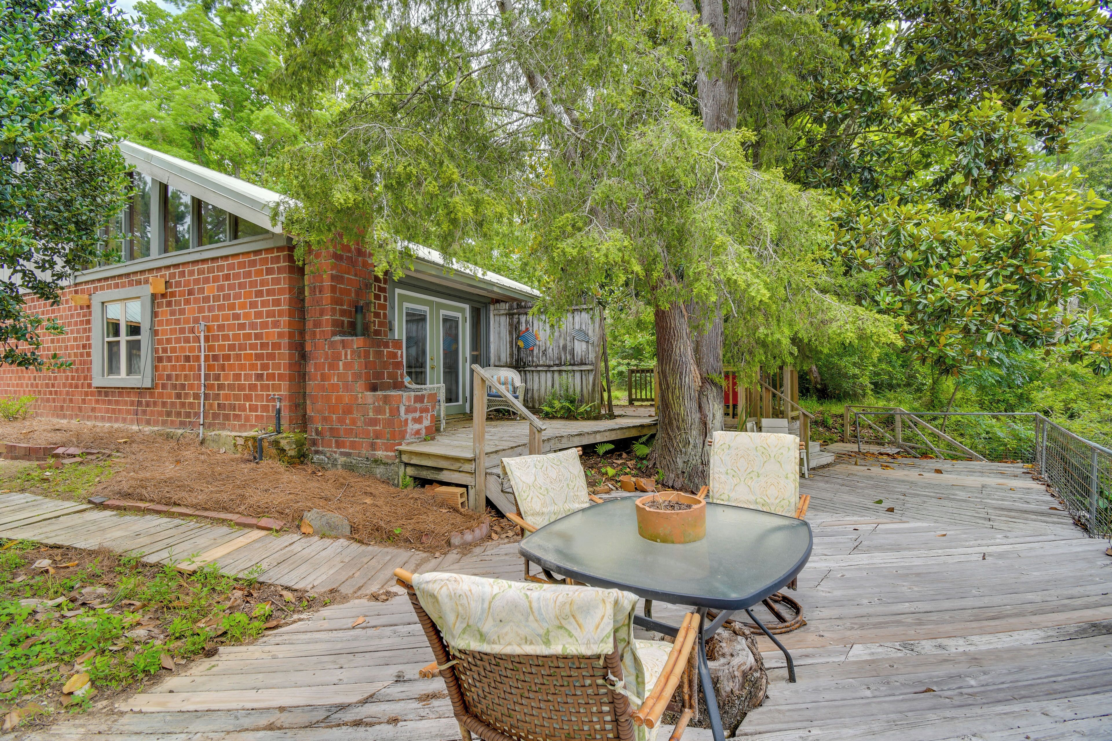 A patio with a round table and wicker chairs, a brick building, and a wooden deck.