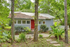 A small house with a red door, surrounded by trees and plants. - Cozy Fairhope Retreat w/ Patio & Grill! (Fairhope)