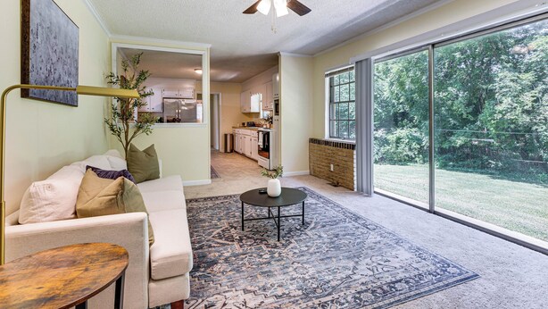 A spacious living room with a large window, a ceiling fan, and a view of the backyard. - Spacious Yard! Family-friendly Huntsville Home (Huntsville)