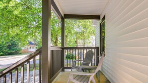 A covered porch with two chairs, a table, and a view of a street and trees. - Charming Greenville Home w/ Yard: 3 Mi to Downtown (Greenville)