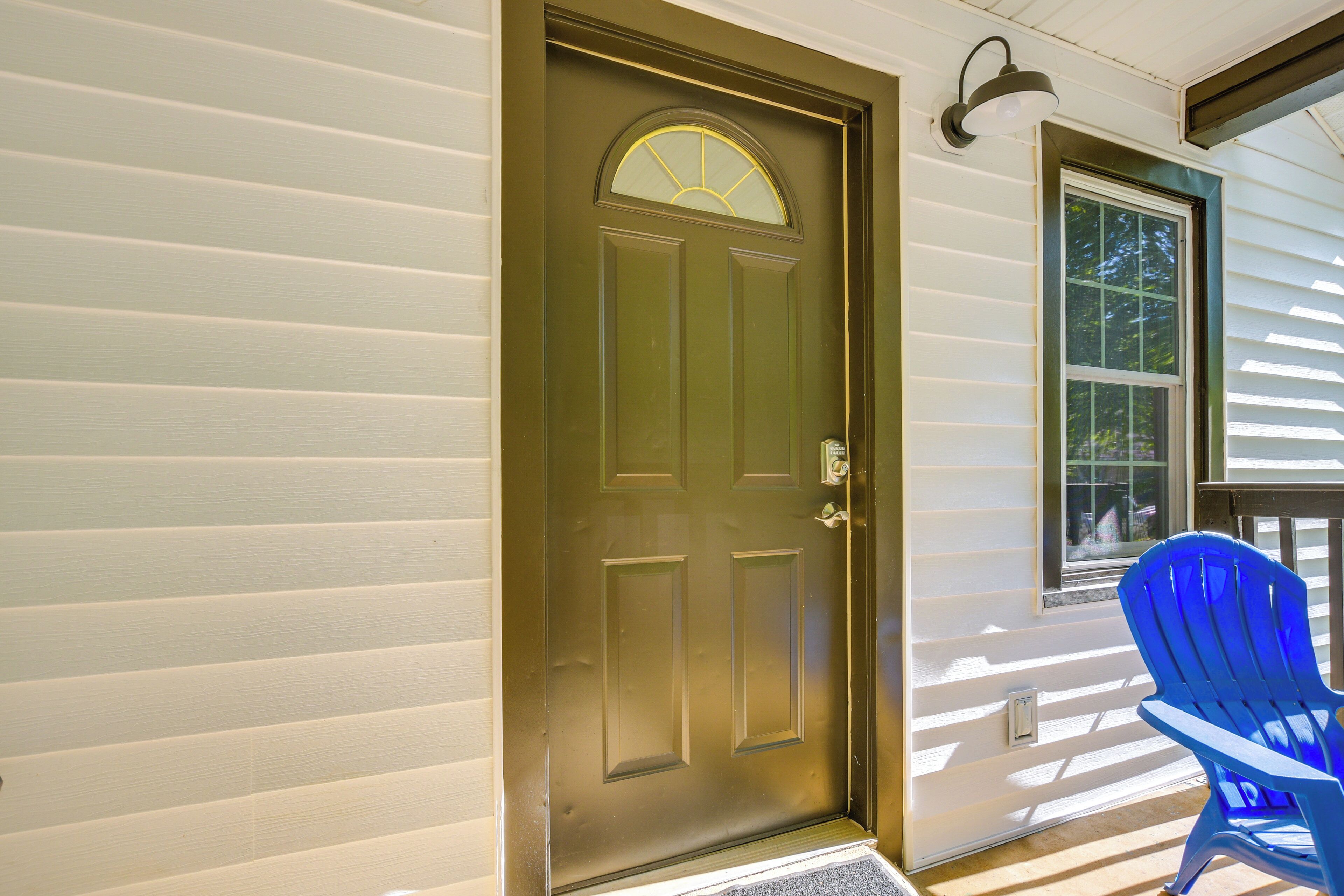 A front door with a window to the right, a blue chair outside, and a porch with a light fixture.