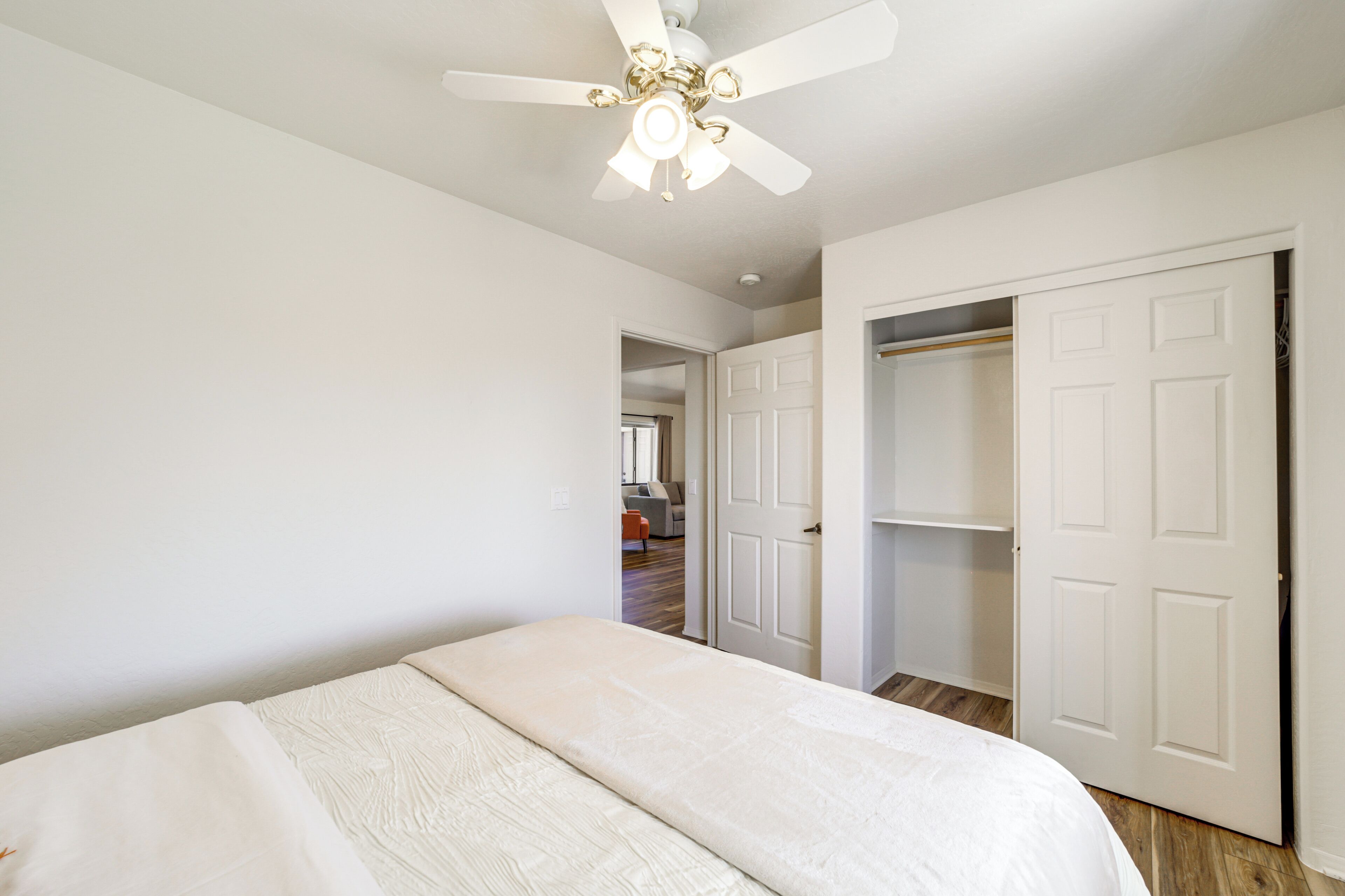 A bedroom with a bed, a ceiling fan, and a closet.