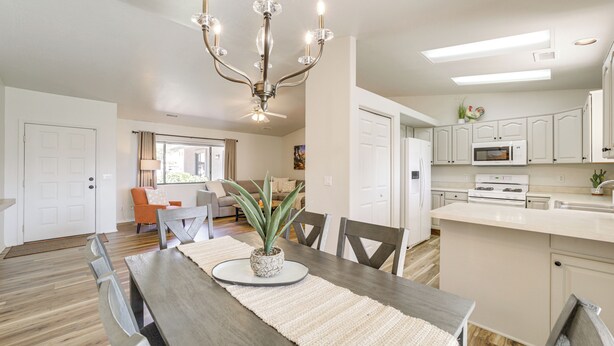 A modern kitchen with a central island, white cabinetry, and a chandelier. - Hike, Shop & Unwind: Cottonwood Home w/ Patio! (Cottonwood)