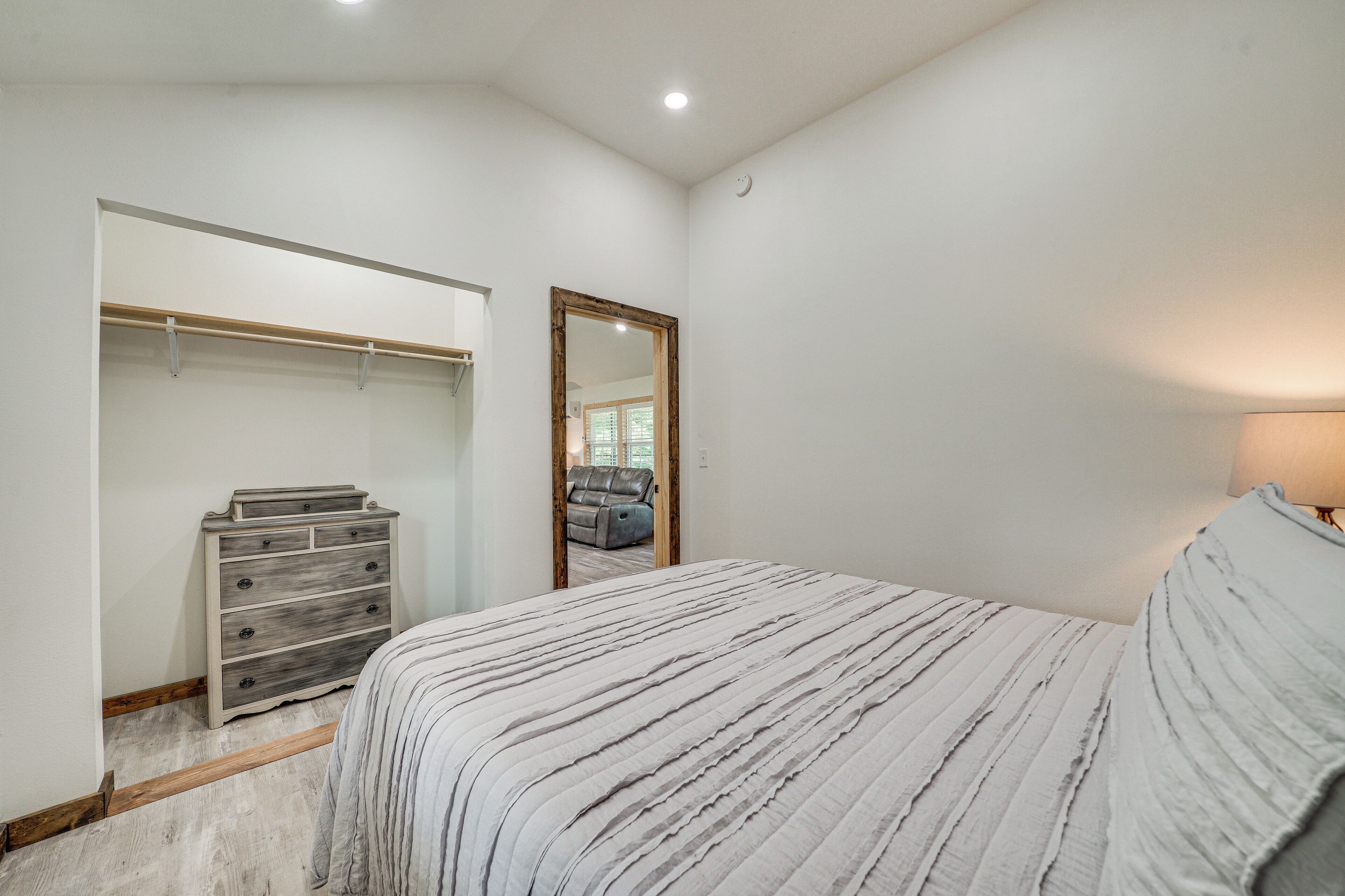 A bedroom with a bed, a dresser, a closet, and a mirror.
