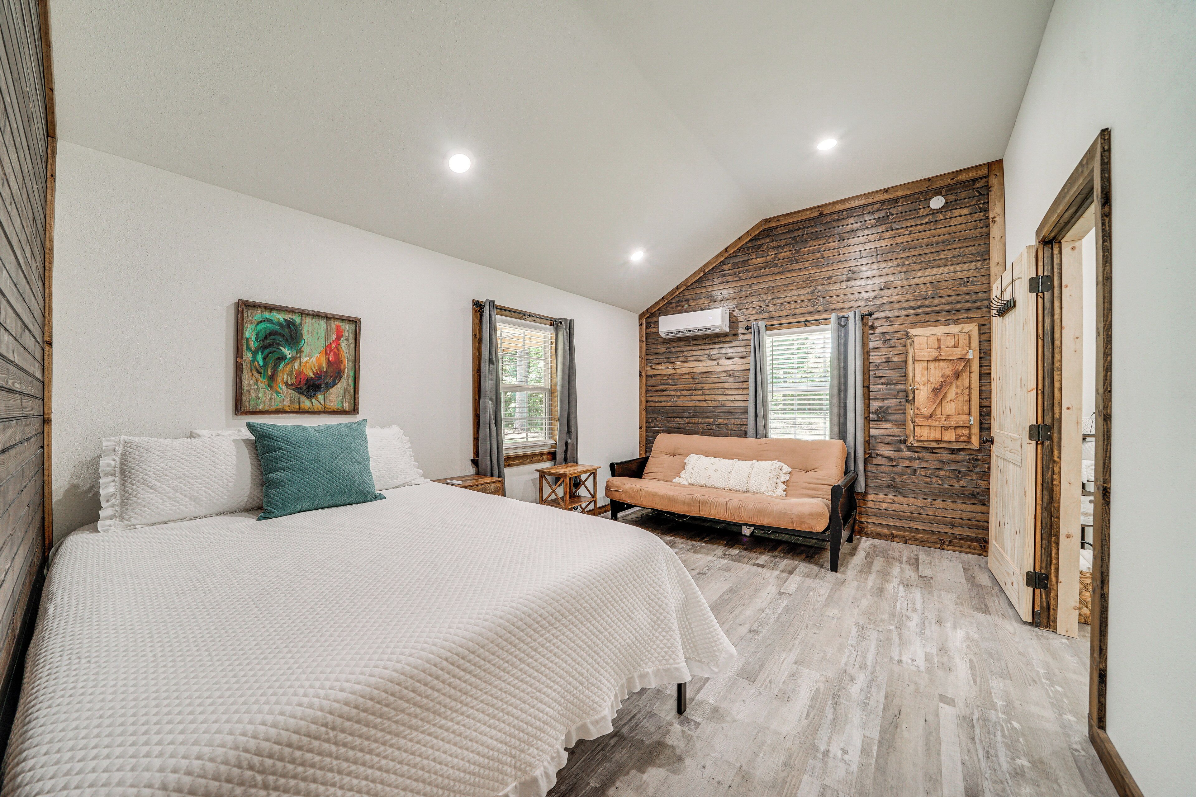 A bedroom with a large bed, a sofa, wooden walls, and a sloped ceiling.
