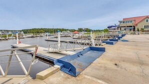 A marina with docked boats, a pier with a blue ramp, and a building with a red roof.
