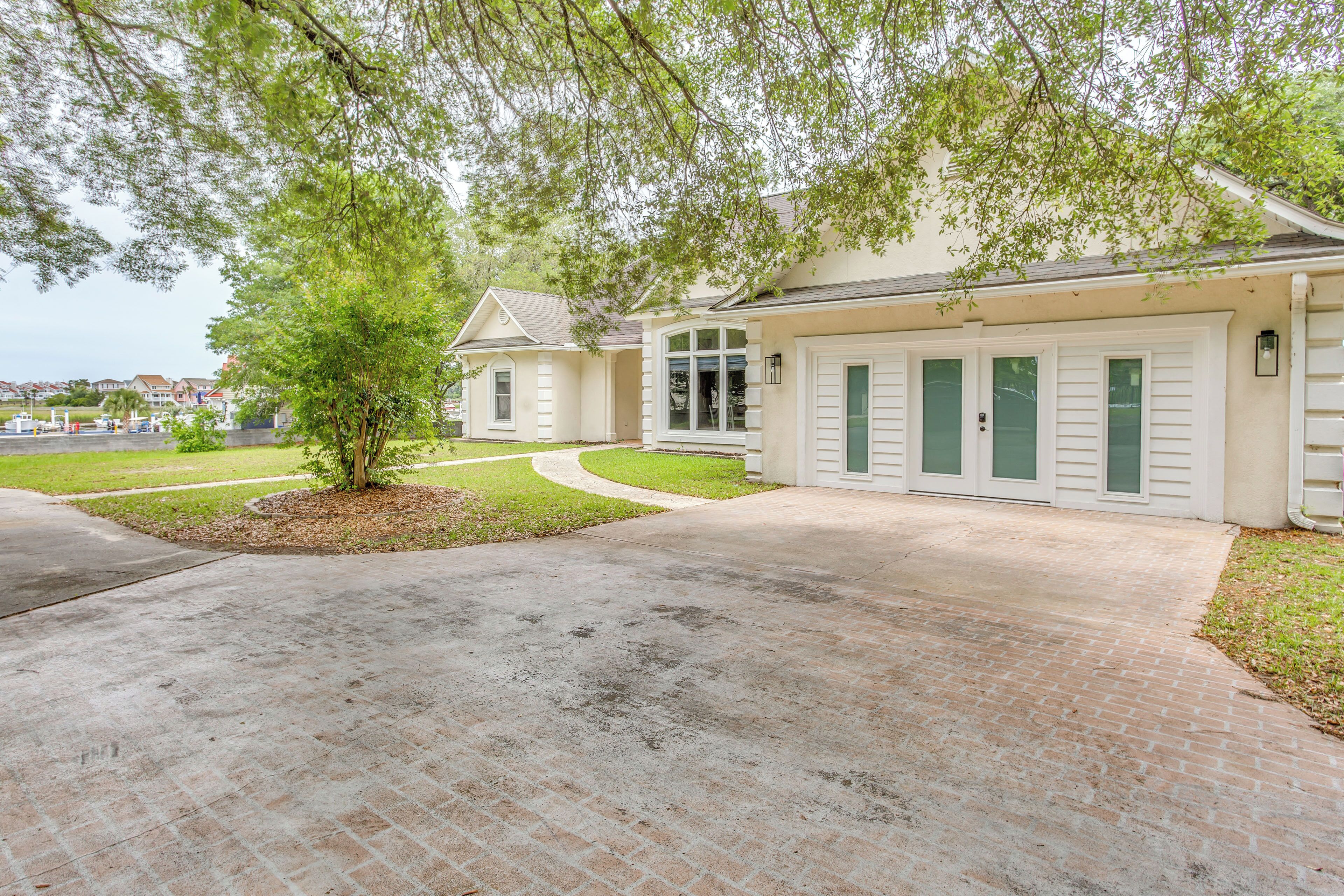 A two-story house with a brick driveway, a small tree, and a well-maintained lawn.