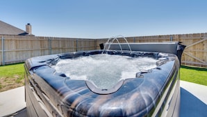 Ein Whirlpool in einem Garten mit Holzzaun und einem Haus im Hintergrund.