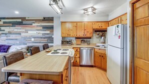 A modern kitchen with wooden cabinets, a stainless steel dishwasher, and a white refrigerator. - Beach & Lake Access: Brainerd Townhome (Brainerd)