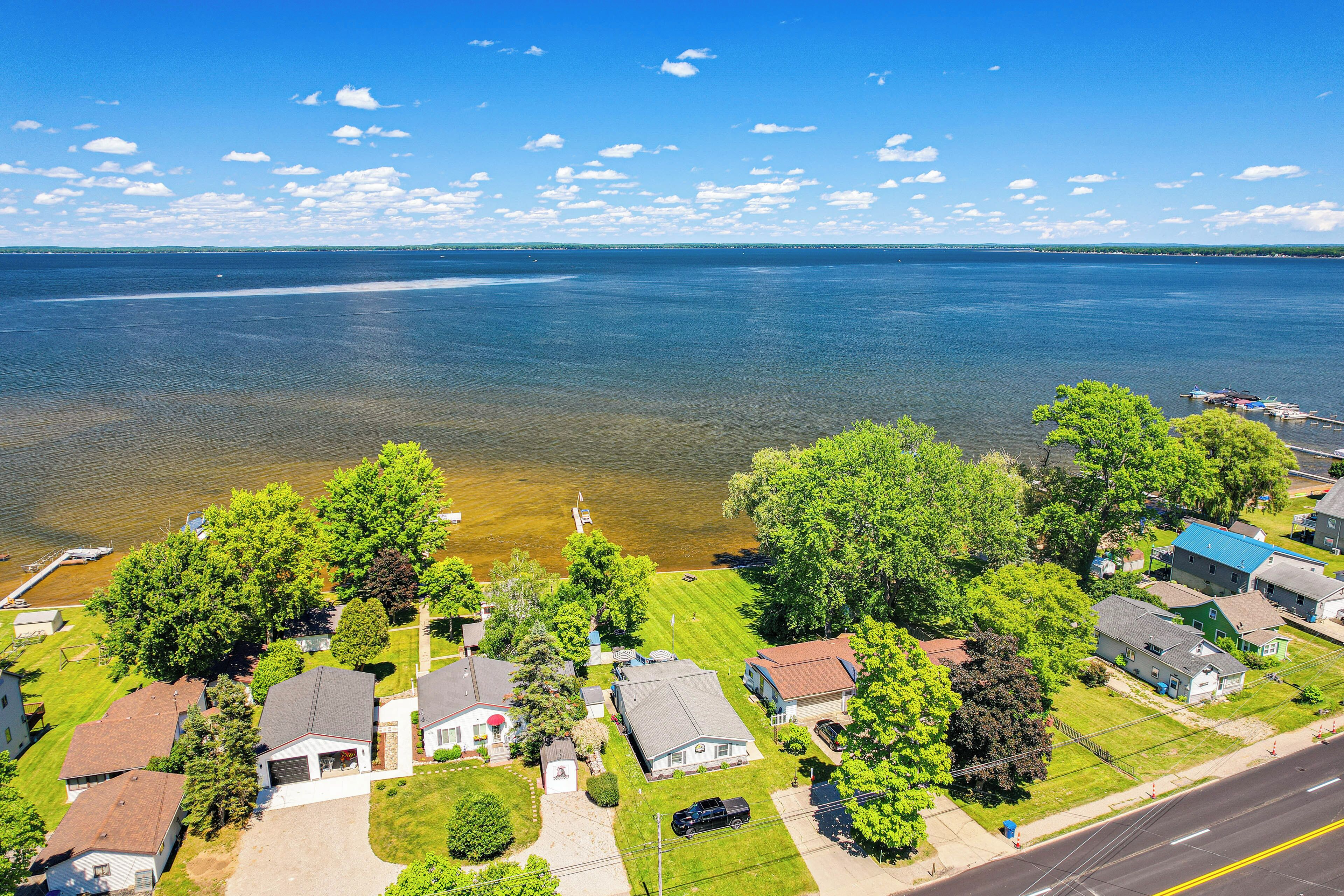 An aerial view of a residential area with houses, a road, and a large body of water.
