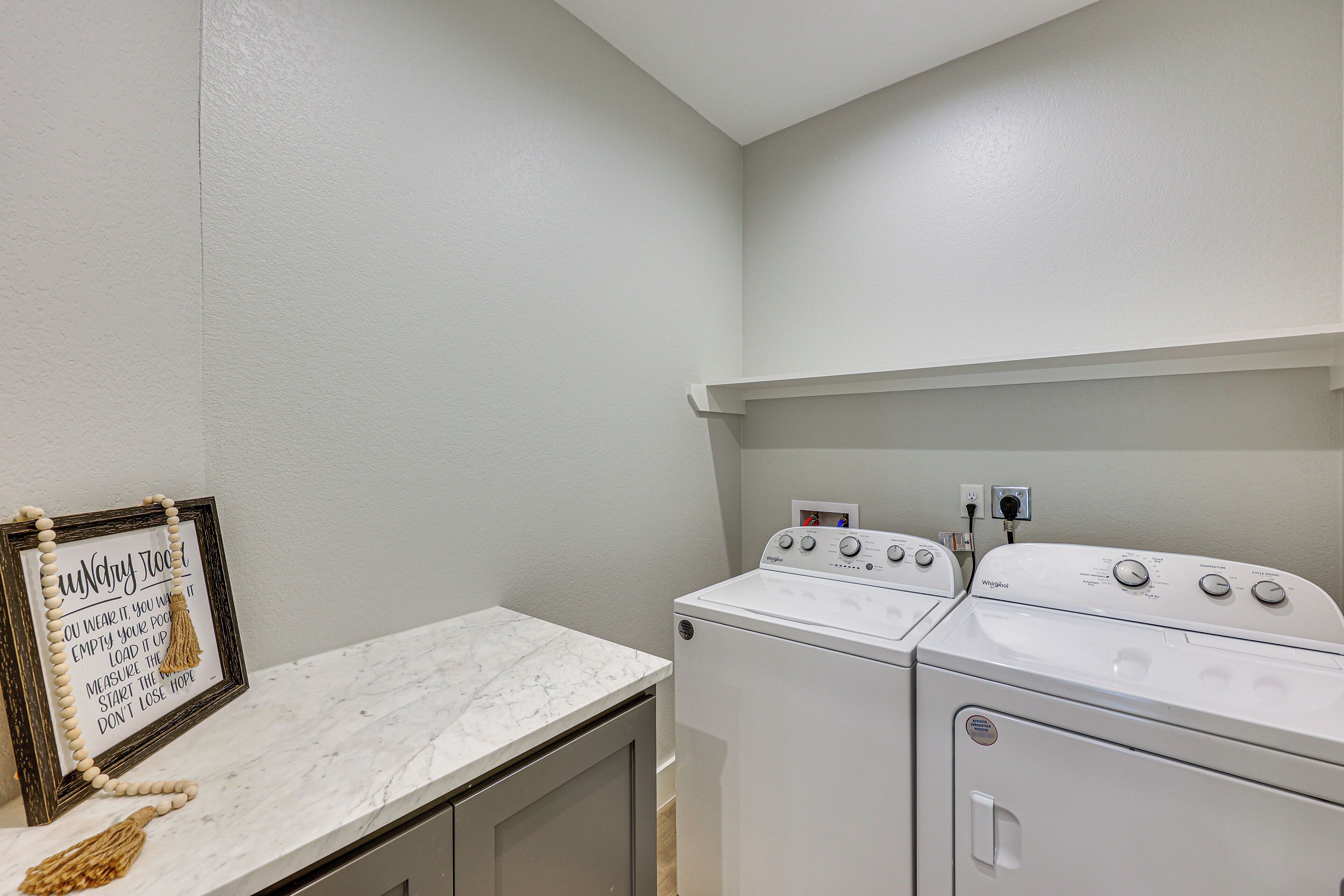A laundry room with a white washing machine, a dryer, and a marble countertop.