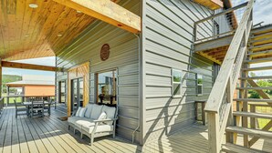 A wooden deck with outdoor furniture, a staircase, and a covered area with a view of the landscape.