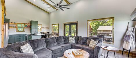 A spacious living area with a sectional sofa, a round coffee table, and a ceiling fan.