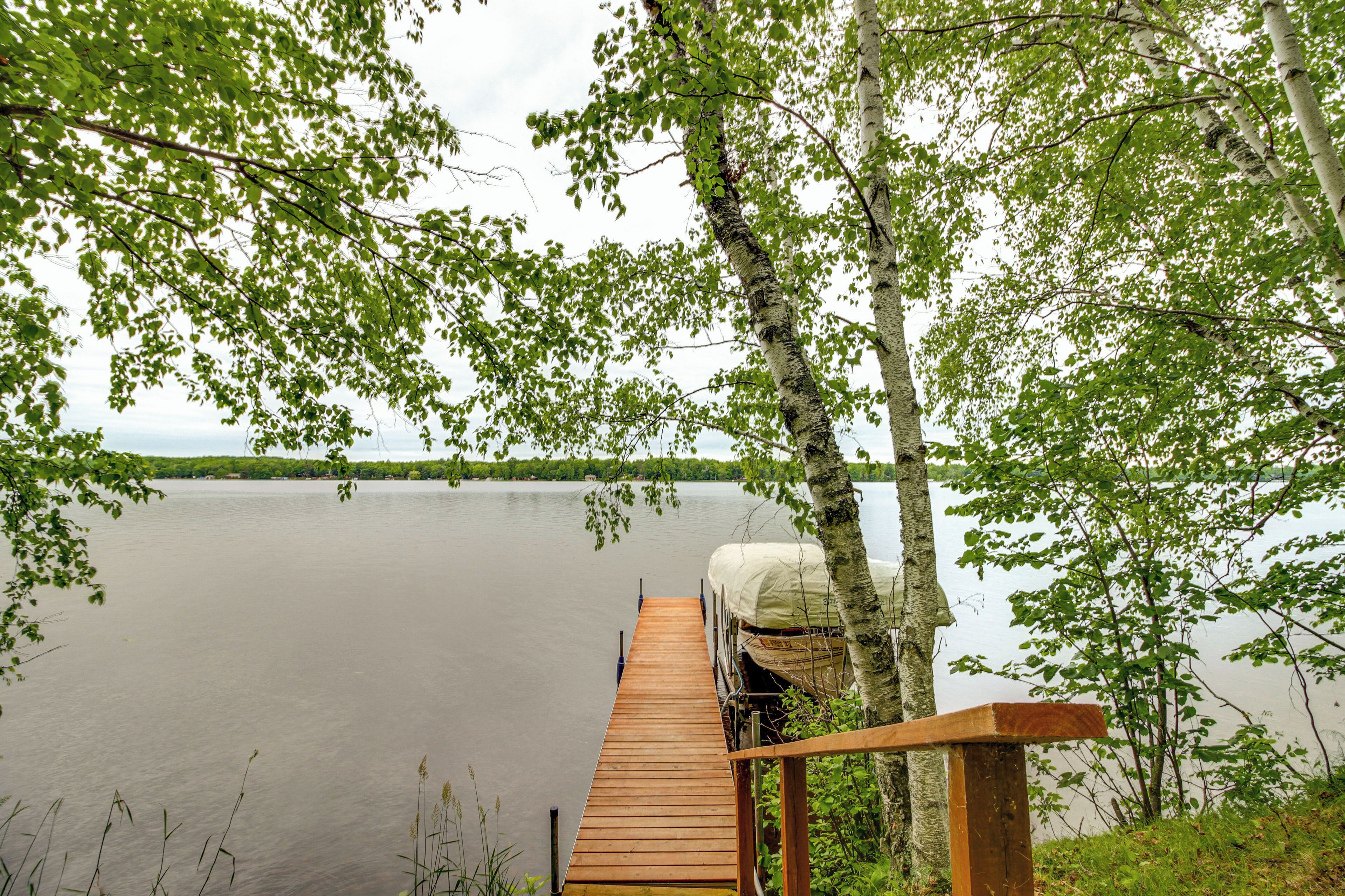 A wooden dock extending into a calm lake, surrounded by trees.