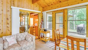 A wooden cabin interior with a sofa, a dining table, and a window overlooking a deck. - Sullivan Lake Cabin w/ Pierz & Hillman Access! (Hillman)