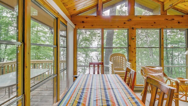 A spacious room with a large bed, wooden furniture, and large windows offering a view of the outdoors. - Sullivan Lake Cabin w/ Pierz & Hillman Access! (Hillman)